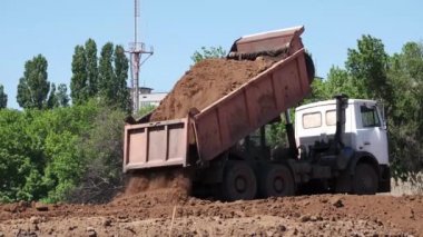 Karayolu inşaatı için çöp kamyonu yere toprak boşaltıyor. Ağır Sanayi Makineleri Yeni Bir Yol İnşa Ediyor.