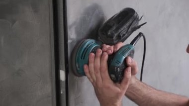 Yetenekli işçi duvarları elektrikli el değirmeni makinesiyle cilalıyor. Usta bir binada tamirat yapıyor..