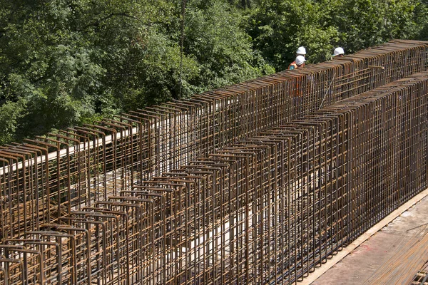 Trabajadores de la construcción entre barras de acero — Foto de Stock