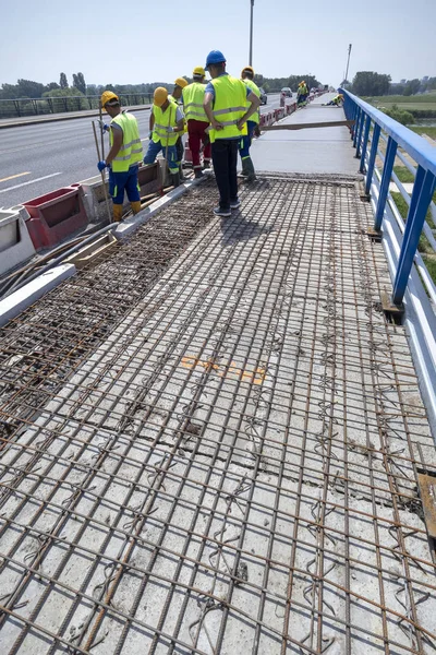 上下班时间 在一座老桥上安装黄色钢盔混凝土和光滑新鲜混凝土的工人 — 图库照片