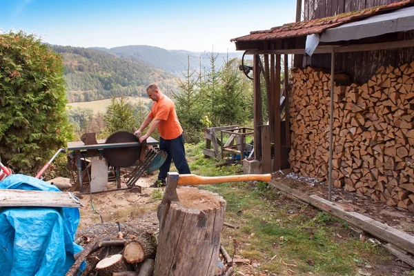 Man snijdt hout. Man snijden brandhout, voorbereiding voor de winter. Brandhout voor verwarming. — Stockfoto