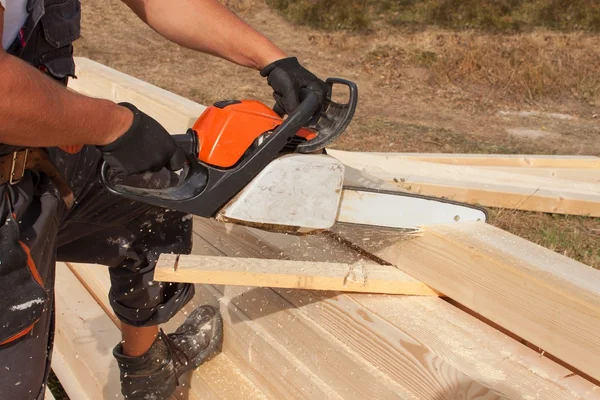 Construction Worker Cutting Beam with saw. Workers cutting timber wood with chainsaw. Saw sawing timber.