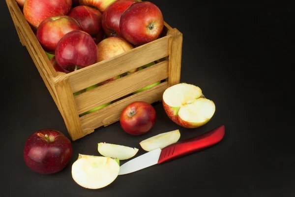 Manzanas rojas frescas de otoño en caja de madera de estilo granja. Venta de productos agrícolas. Publicidad para la venta de frutas. Cuchillo de cerámica fruta . — Foto de Stock