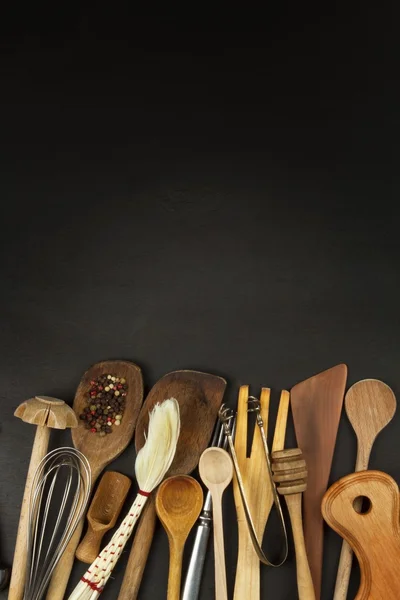 Ustensiles de cuisine sur table en bois. Les outils cuisinent. Il faut cuisiner. Ensemble d'ustensiles de cuisine en bois sur fond en bois noir . — Photo