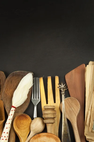 Naczynia kuchenne na drewnianym stole. Narzędzia gotować. Trzeba gotować. Zestaw drewniane naczynia na czarnym tle drewnianych. — Zdjęcie stockowe