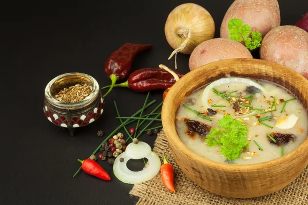 Homemade potato soup with mushrooms. Bowl with potato soup on wooden table. Food preparation.