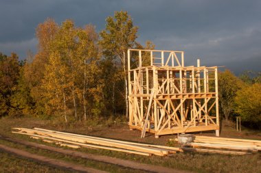 Güneşli akşam bir ahşap evin inşaat sahasında. Bitmemiş ev.