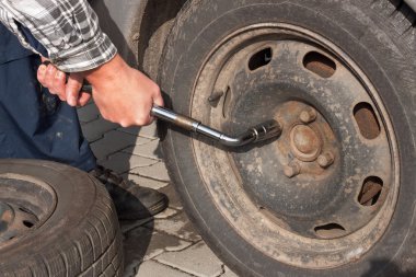 Adam kış Lastik tekerlekli anahtar ile değişiyor. Arabayı kışa hazırlanıyor. Delinmiş lastik tamiri.