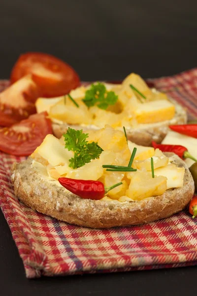 Zwei Käsesorten auf Brot. gesundes Frühstück auf dem Küchentisch. Brot mit Käse Kirschtomaten und Chili. — Stockfoto