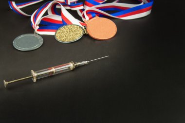 Şırınga ve madalya. Sporda doping. Spor için anabolik steroid kötüye. Anabolik steroidler ahşap bir masaya döküldü. Dolandırıcılık spor.