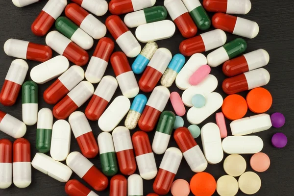 Vista detalhada de pílulas multicoloridas. Indústria farmacêutica. Pílulas coloridas em fundo preto — Fotografia de Stock
