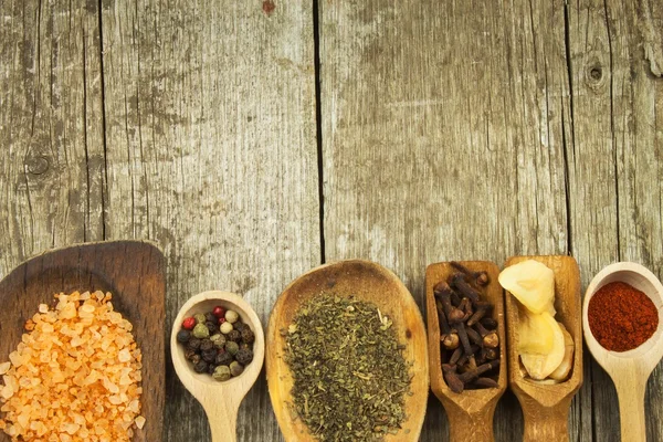 Spice in Wooden spoon. Herbs. Cinnamon and other on a wooden rustic background. Pepper. Large collection of different spices and herbs. Salt, paprika. Sale of spices. — Stockfoto