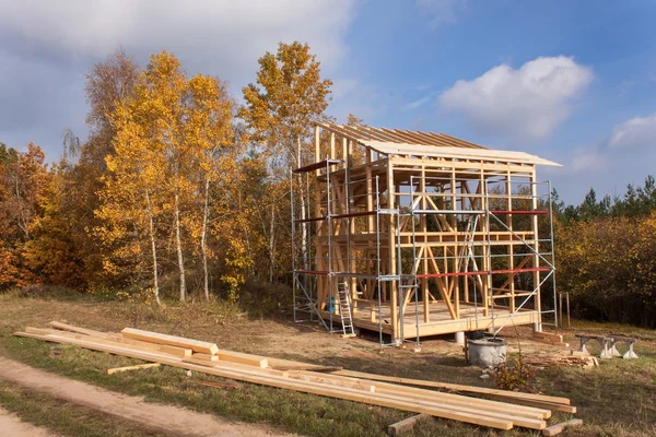 Andamios metálicos alrededor de la casa sin terminar. Construcción de casa ecológica. Marco de madera de la casa en construcción.Construcción nueva enmarcada de una casa. Casa de madera en proceso de construcción — Foto de Stock