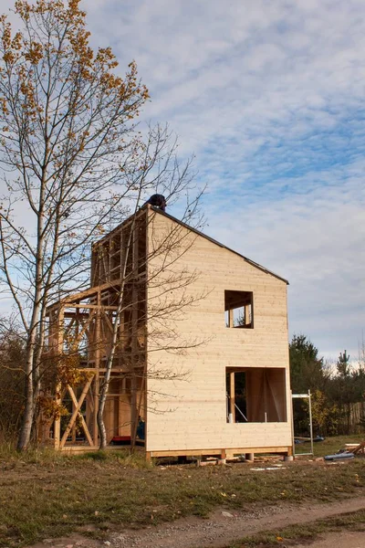 Bouw van ecologische huis. Externe werk op de envelop van het gebouw. De houten structuur van het huis in de buurt van het bos. — Stockfoto