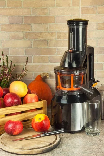 Juicer and apple juice. Preparing healthy fresh juices. Home juicing apples in the kitchen. Processing autumnal fruit.