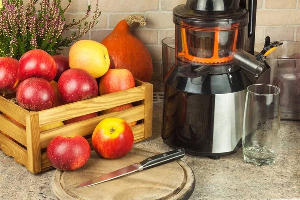 Juicer and apple juice. Preparing healthy fresh juices. Home juicing apples in the kitchen. Processing autumnal fruit.