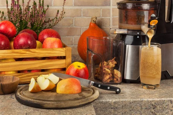 Saftpresse und Apfelsaft. Zubereitung gesunder frischer Säfte. Äpfel in der Küche entsaften. Verarbeitung herbstlicher Früchte. — Stockfoto