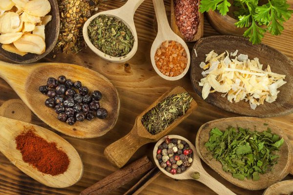 Various kinds of spices on the kitchen table. Seasoning food. Sales of exotic spices. Advertising on spices. Powder spices on spoons in wooden table background.