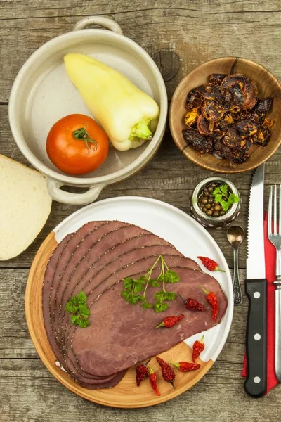 冷烤牛肉木制的桌子上。美味的牛肉。准备冷点心。传统的餐。牛肉烤牛肉加青辣椒、 红辣椒及蔬菜. — 图库照片