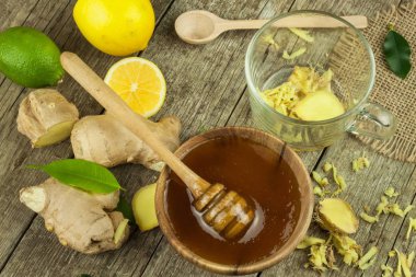 Zencefil çayı grip karşı hazırlanıyor. Soğuk algınlığı için geleneksel tedavi. Ahşap masa zencefil, limon ve bal kase. Rustik ahşap arka plan. Ev Eczanesi.