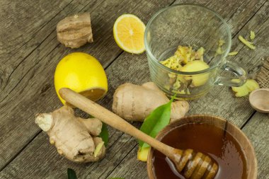 Zencefil çayı grip karşı hazırlanıyor. Soğuk algınlığı için geleneksel tedavi. Ahşap masa zencefil, limon ve bal kase. Rustik ahşap arka plan. Ev Eczanesi.