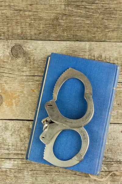 Book and handcuffs on a wooden table. The concept of punishment and justice. Punishment for a crime. Corruption and punishment. Arrest criminals. — Stock Photo, Image