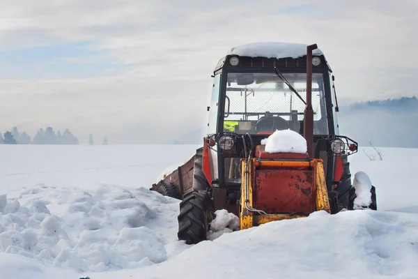 Old tractor under the snow. Snow calamity in transport. Frozen diesel engine.