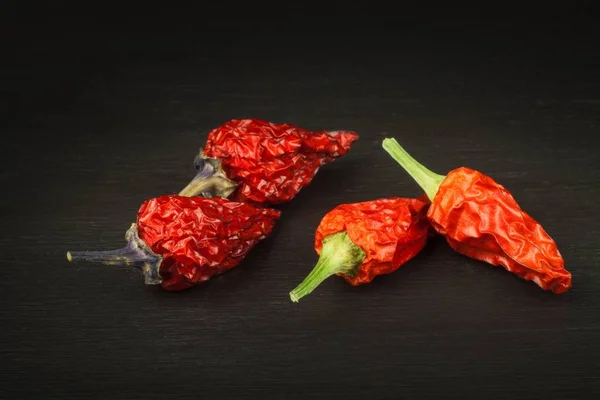 Spice reklamy. Sušené chilli na černý dřevěný stůl. Prodej koření. Pěstování paprik. — Stock fotografie