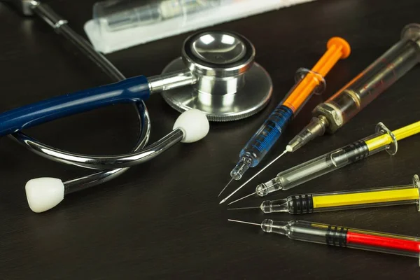 Jeringa en una tabla de madera. Tratamiento del cáncer. Vacunación contra la gripe. Instrumentos médicos y fonendoscopio — Foto de Stock