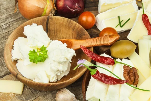 Refrescos de diferentes tipos de queso. Desayuno saludable de productos lácteos. Quesos en rodajas sobre una mesa de madera . — Foto de Stock