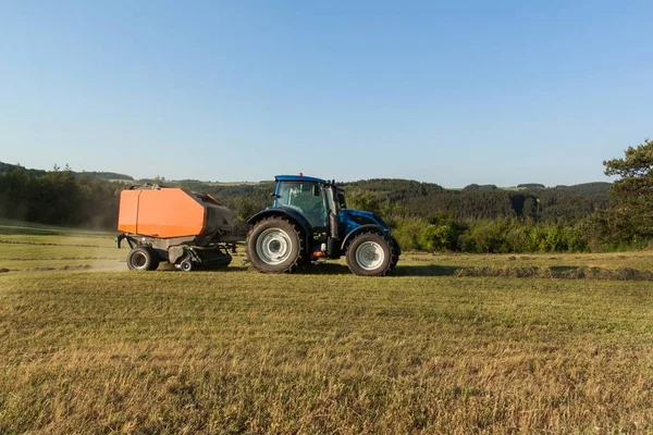 Blauwe trekker op de wei... Werk in de landbouw op de boerderij in de Tsjechische Republiek. — Stockfoto