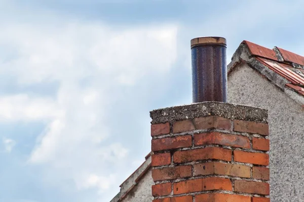 Old brick chimney on the roof. Air pollution. — Stock Photo, Image