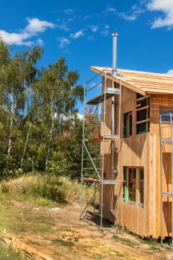Paslanmaz çelik baca ekolojik bir ev bina. Enerji tasarrufu sağlayan ahşap ev. Cottage forest yakınındaki inşaatı.