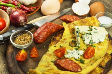 Ahşap oyun tahtası lezzetli dolma omlet. Kızarmış yumurta omlet kiraz domates, sarımsak ve biber ile. Besleyici Kahvaltı.