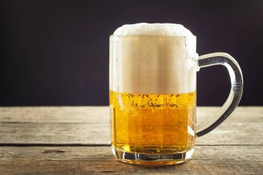 Bira ahşap bir masa üzerinde bir bardak içine dökme. Alkollü içecekler. Alkolsüz bira. Bira Bar satışı.