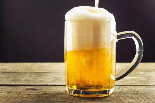 Nalil pivo do sklenice na dřevěný stůl. Alkoholické nápoje. Pivo bez alkoholu. Prodej piva na baru. — Stock fotografie