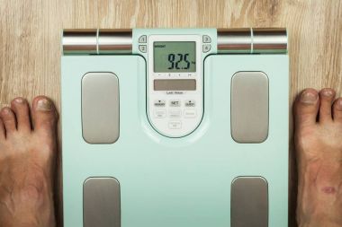 Yaşlı adam modern bir ölçek üzerinde duruyor. Vücut yağ içeriği ölçme. Akıllı tıbbi ağırlık. Obezite kavramı.