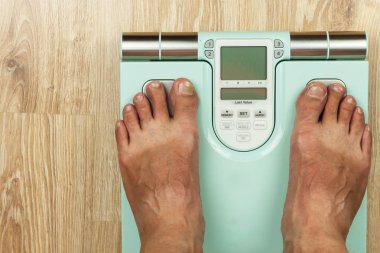 Yaşlı adam modern bir ölçek üzerinde duruyor. Vücut yağ içeriği ölçme. Akıllı tıbbi ağırlık. Obezite kavramı.