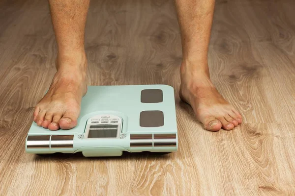 El viejo está de pie en una escala moderna. Medir el contenido de grasa del cuerpo. Peso médico inteligente. El concepto de obesidad . — Foto de Stock