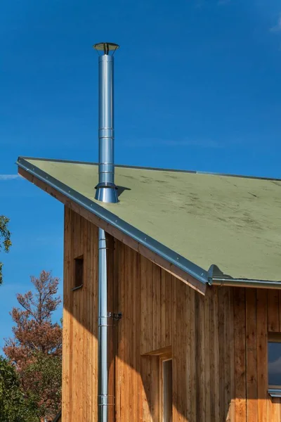 Stainless steel chimney on an organic wooden building near the forest. — Stock Photo, Image