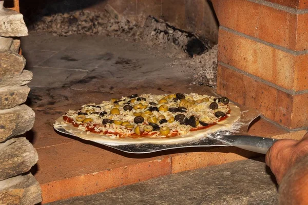 Domestic production of pizza.The man puts pizza in a stone oven. — Stock Photo, Image