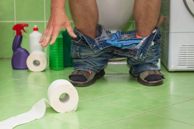 Bir aile evde bir tuvalet üzerinde oturan adam. Karın ağrısı. İshal.