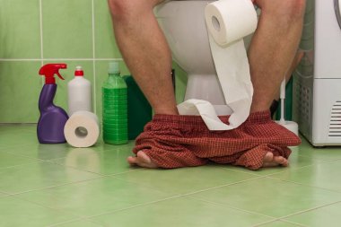 Bir aile evde bir tuvalet üzerinde oturan adam. Karın ağrısı. İshal.