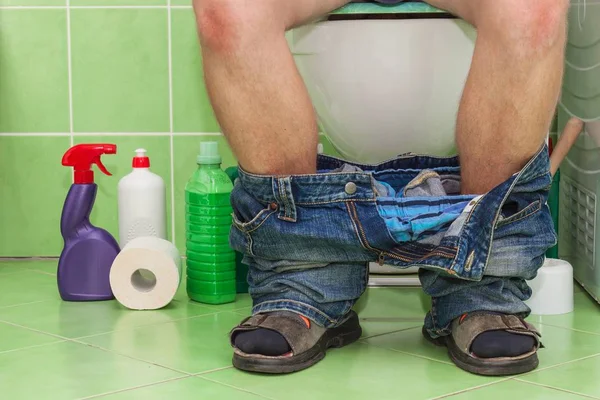 Bir aile evde bir tuvalet üzerinde oturan adam. Karın ağrısı. İshal.