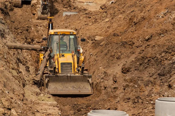 Byggandet av ett nytt avloppssystem system. Bulldozer gräver ett dike för avloppsrör. Byggnadsarbeten. — Stockfoto