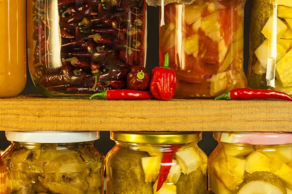 Jars with marinated food and organic raw vegetables. Preserved vegetables on wooden background. Various marinaded food. Life on a rural farm. — Stock Photo, Image