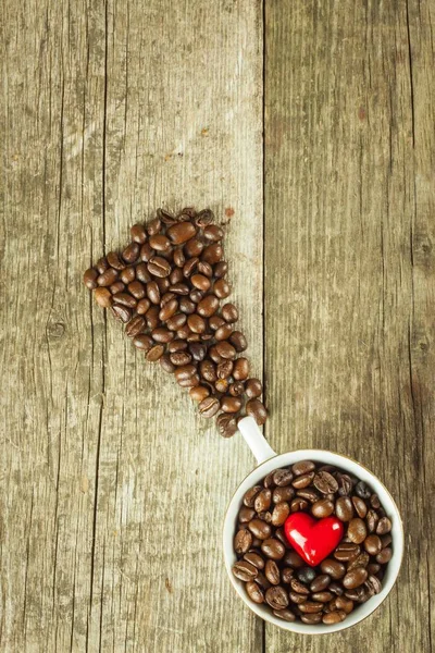 Kaffeebohnen in einer Tasse. verschütteter Kaffee auf einem Holztisch. Verkauf von frischem Kaffee. — Stockfoto