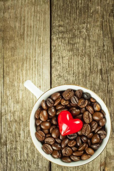 Coffee beans in a cup. Spilled coffee on a wooden table. Sales of fresh coffee. — Stock Photo, Image
