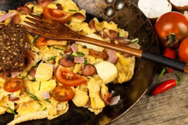 Jambon ve biber Taze karıştırılmış yumurta üzerinde çelik bir tavada biber. Geleneksel besleyici bir kahvaltı. Kalorili yemek.