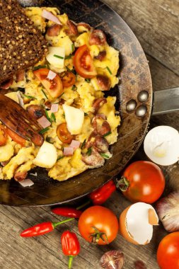 Jambon ve biber Taze karıştırılmış yumurta üzerinde çelik bir tavada biber. Geleneksel besleyici bir kahvaltı. Kalorili yemek.